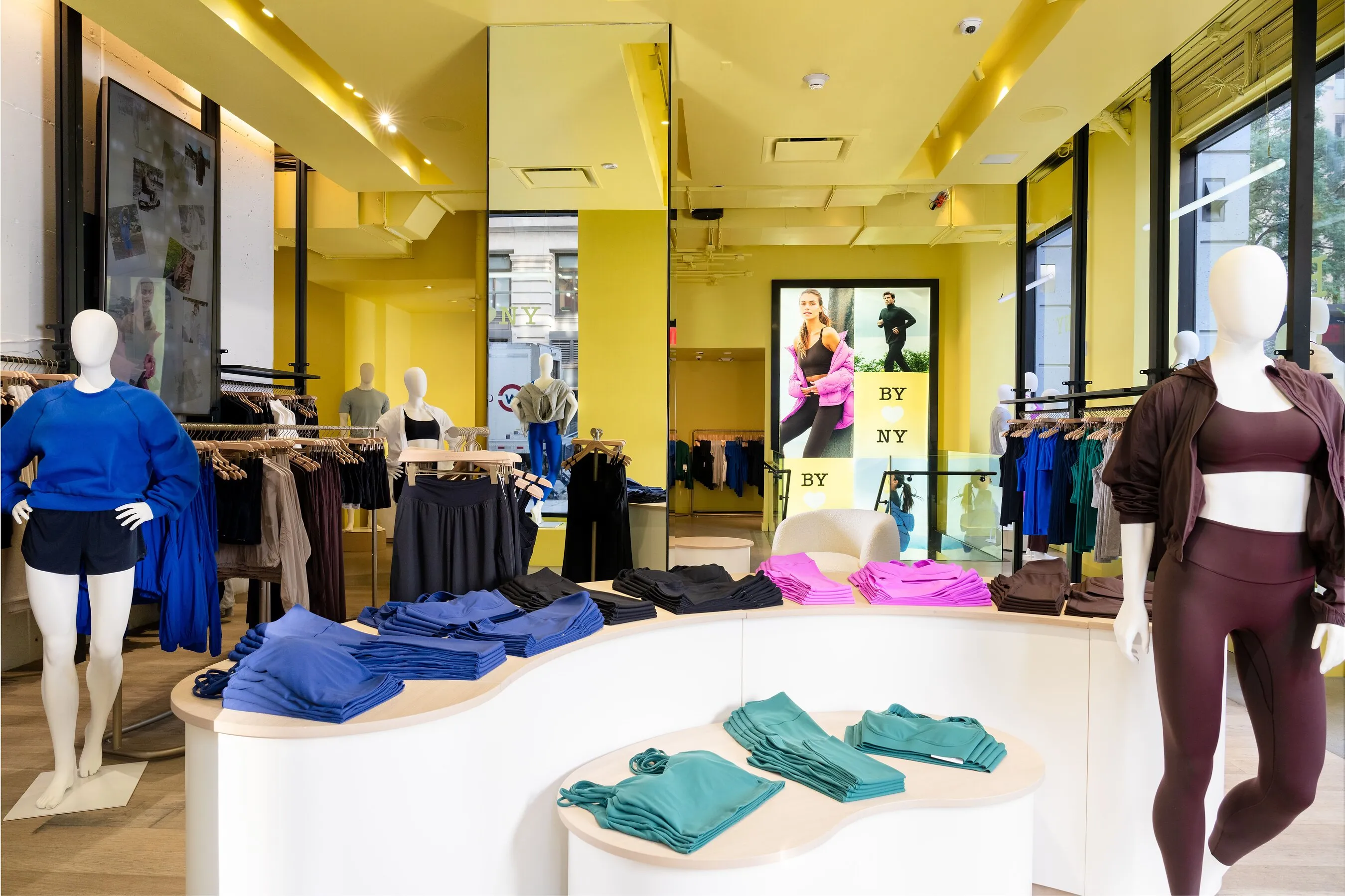 Activewear displayed on mannequins and tables inside a bright yellow clothing store.