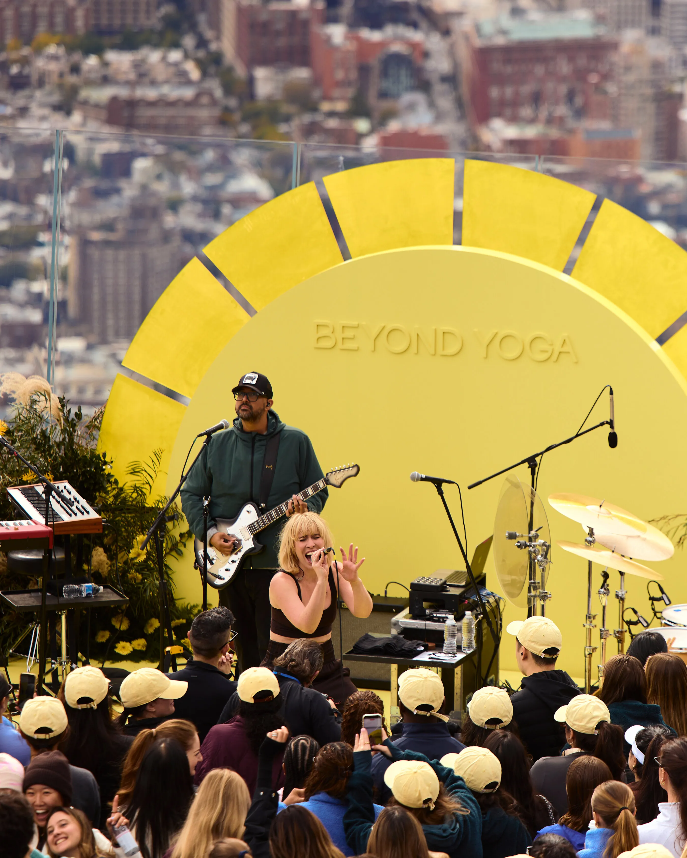 A singer and guitarist perform before a crowd at a yellow Beyond Yoga stage.