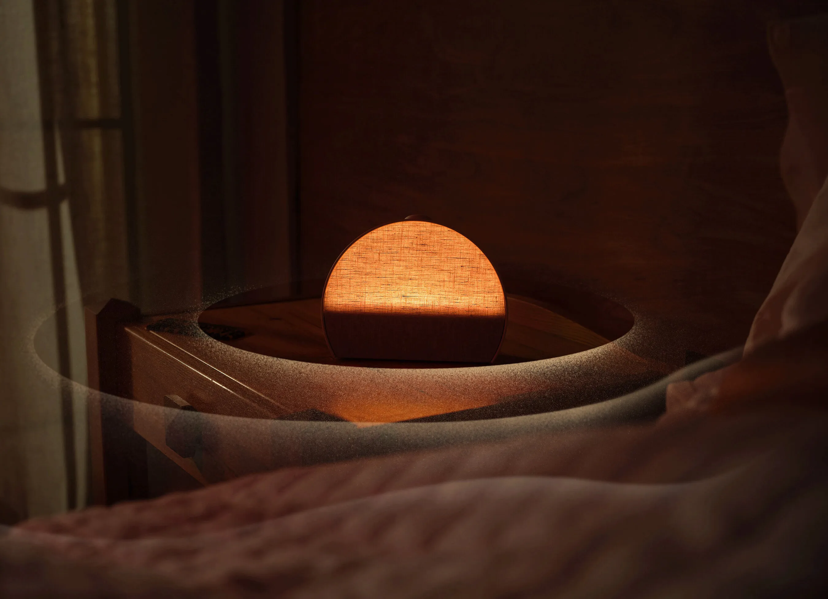 The glowing half-moon Hatch Sleep Clock on a wooden bedside table beside a bed