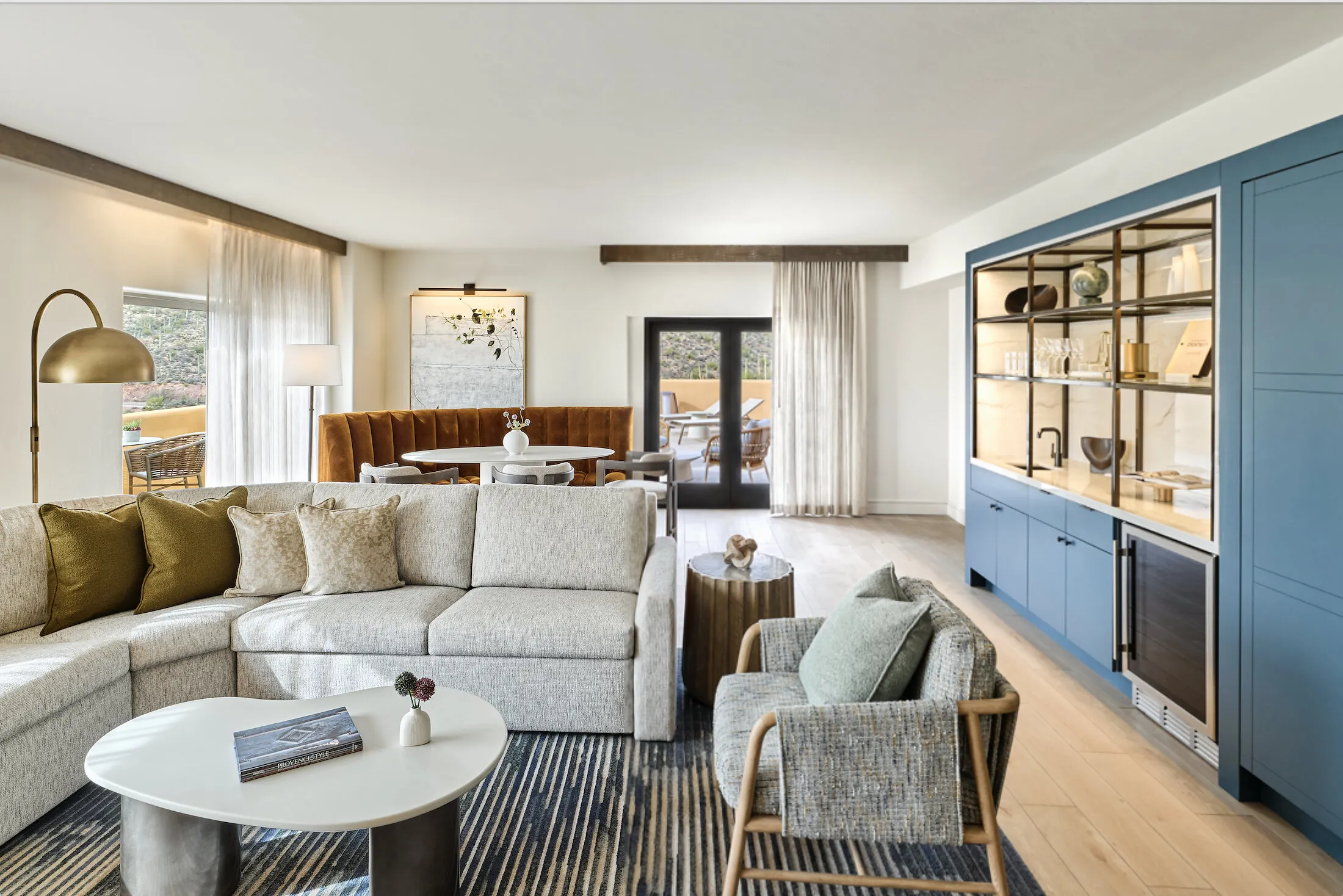 Living room with sofa, armchair, dining nook and blue kitchen cabinetry.