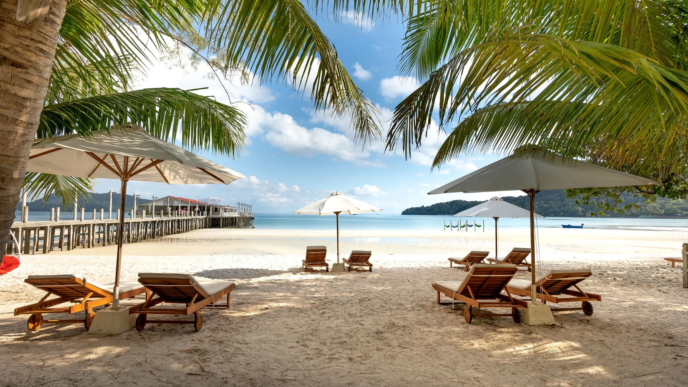 Sun loungers and umbrellas under palm trees on a tropical beach.