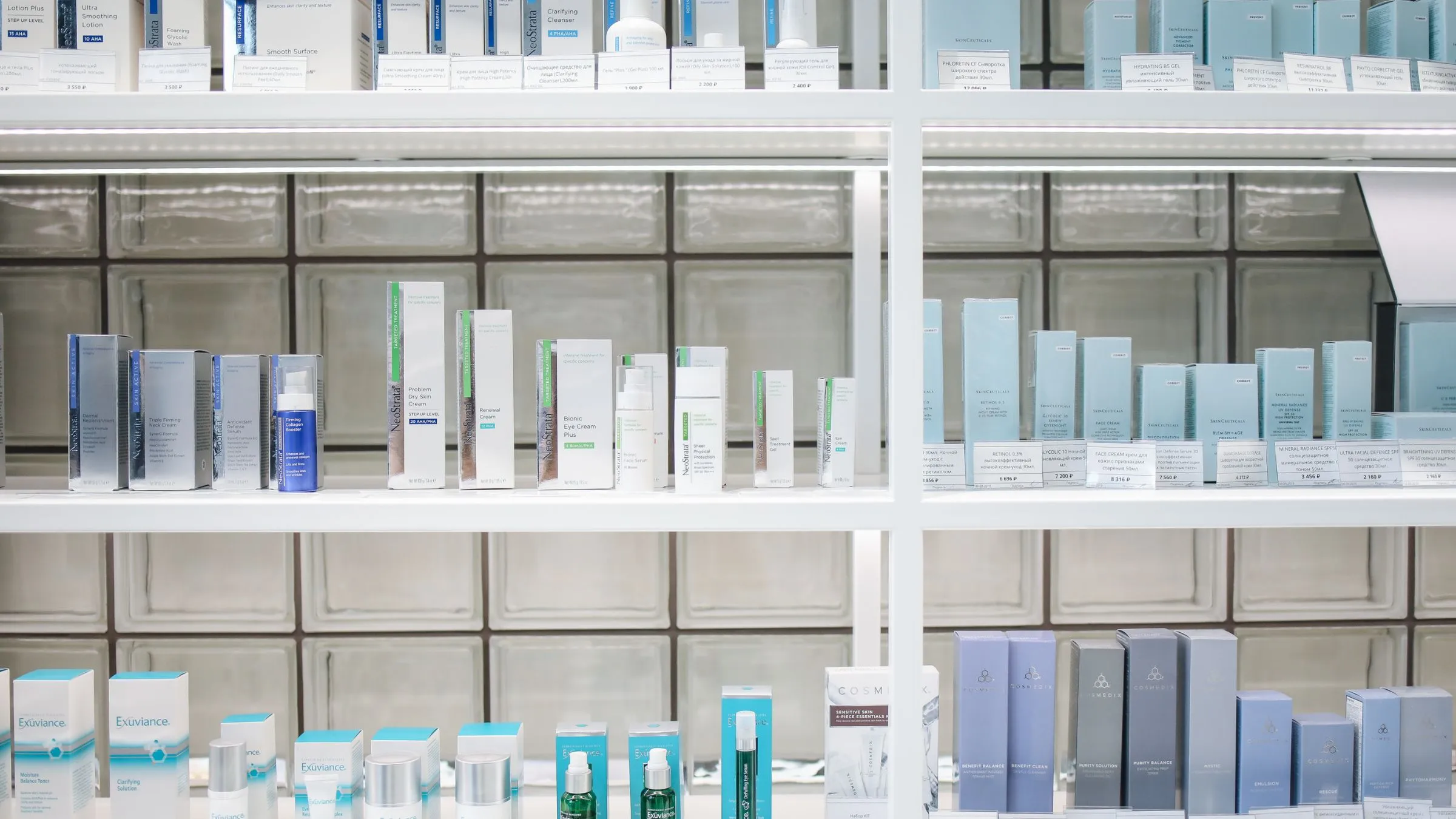 Rows of skincare bottles and boxes on white store shelves.