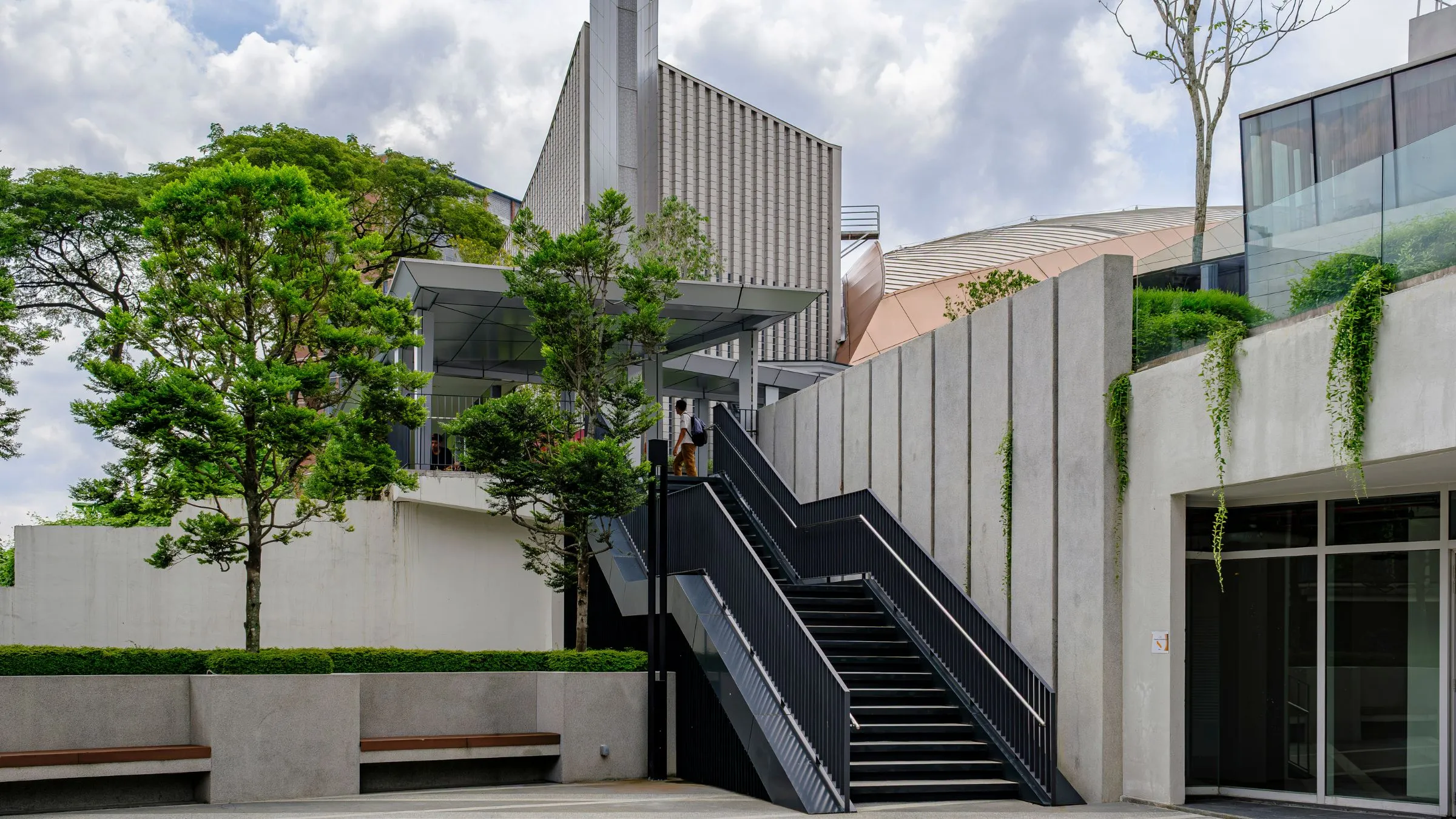 A modern concrete building with trees and planted terraces.