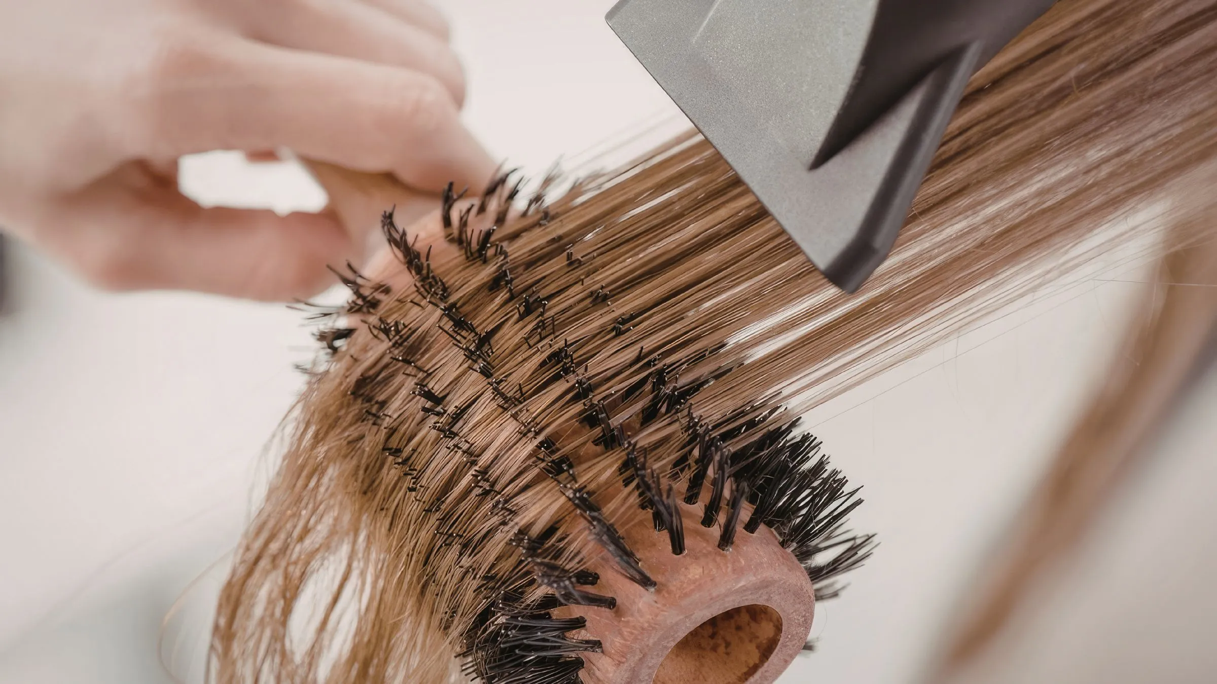 Hair being blow-dried over a round brush in a salon.