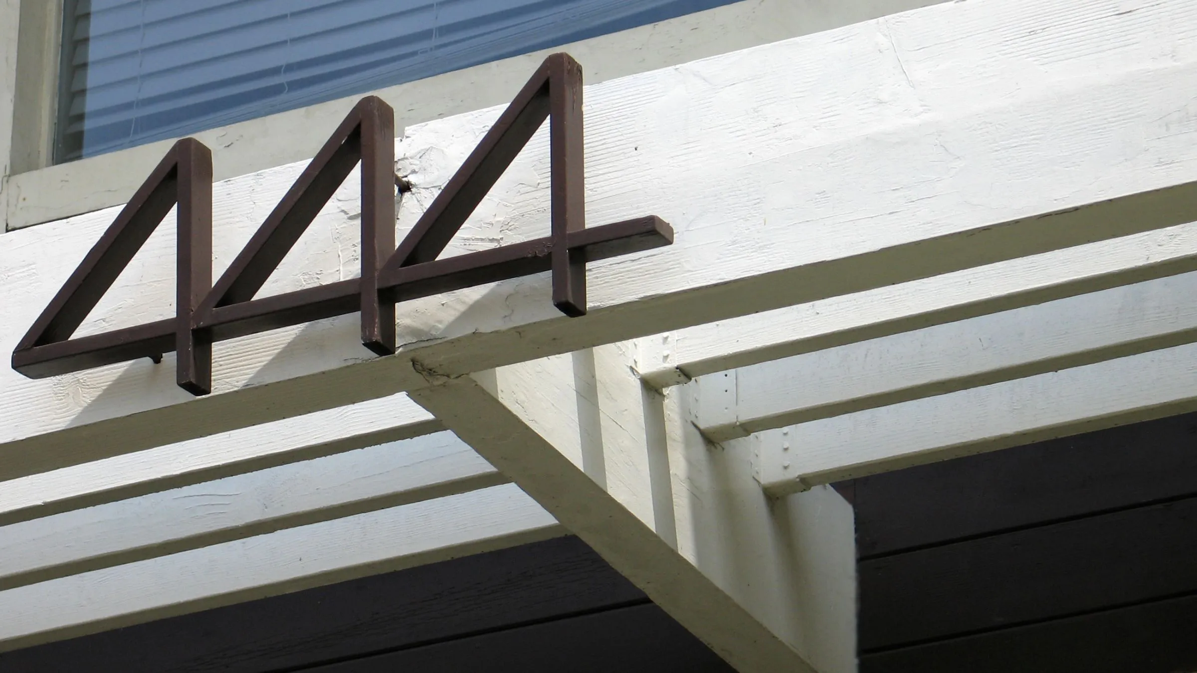 Black house number 444 on a white porch beam.