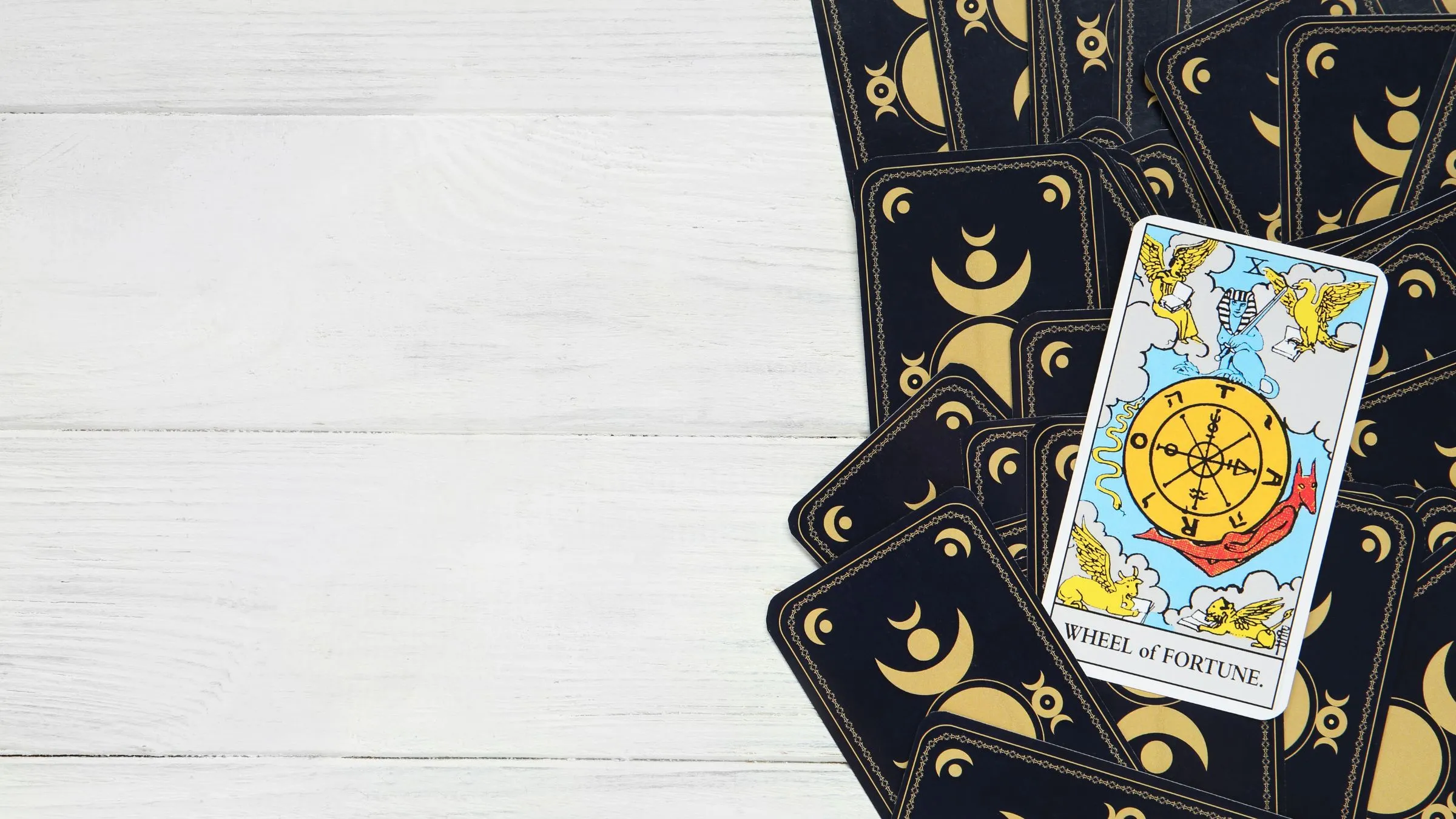 The Wheel of Fortune tarot card on a pile of dark card backs.