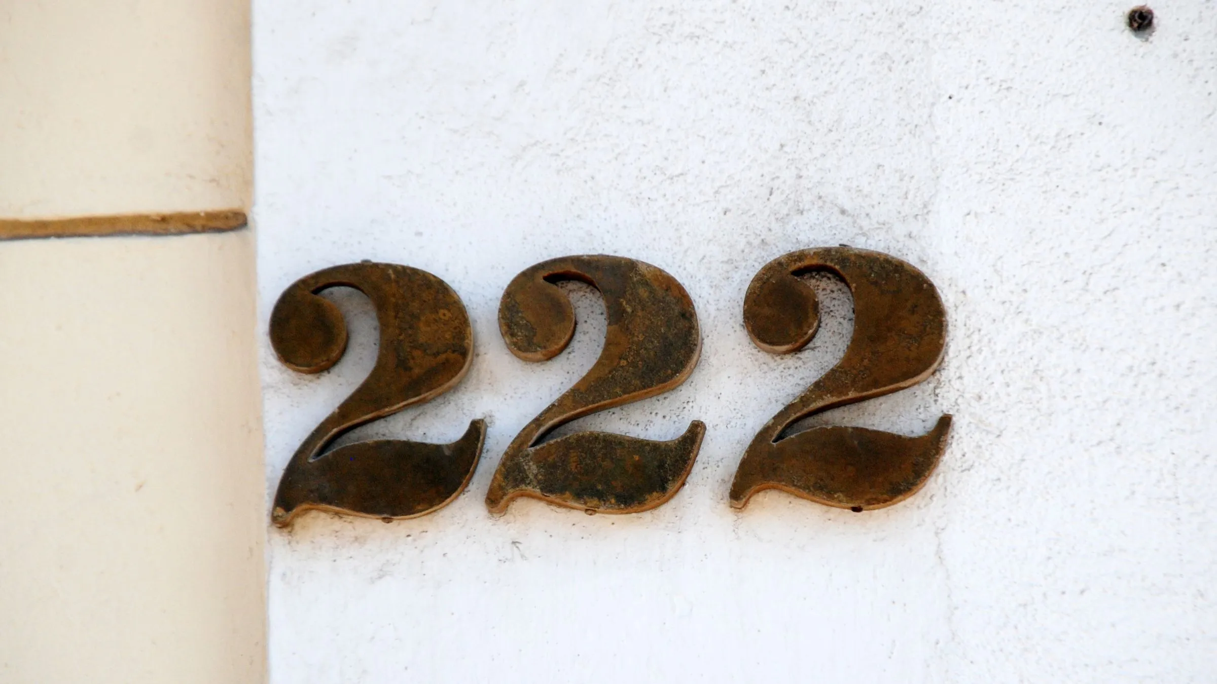 Raised house number 222 on a white wall.