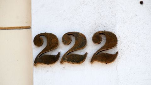 Raised house number 222 on a white wall.