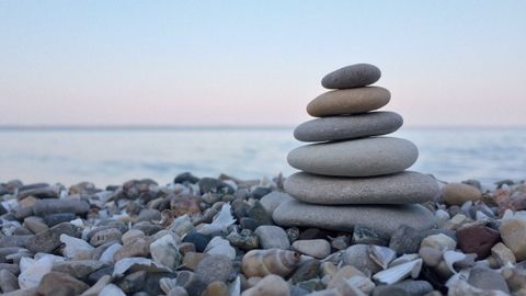 Five smooth stones stacked on a pebble beach at dusk.