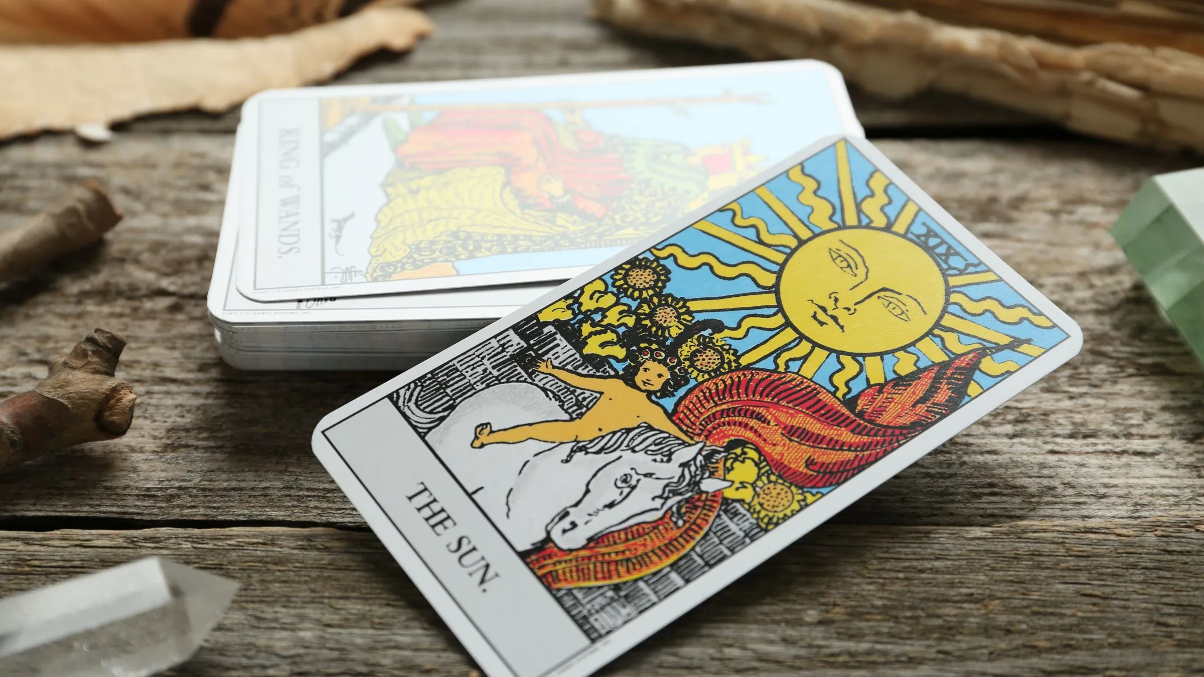 The Sun tarot card resting on a deck on rustic wood.