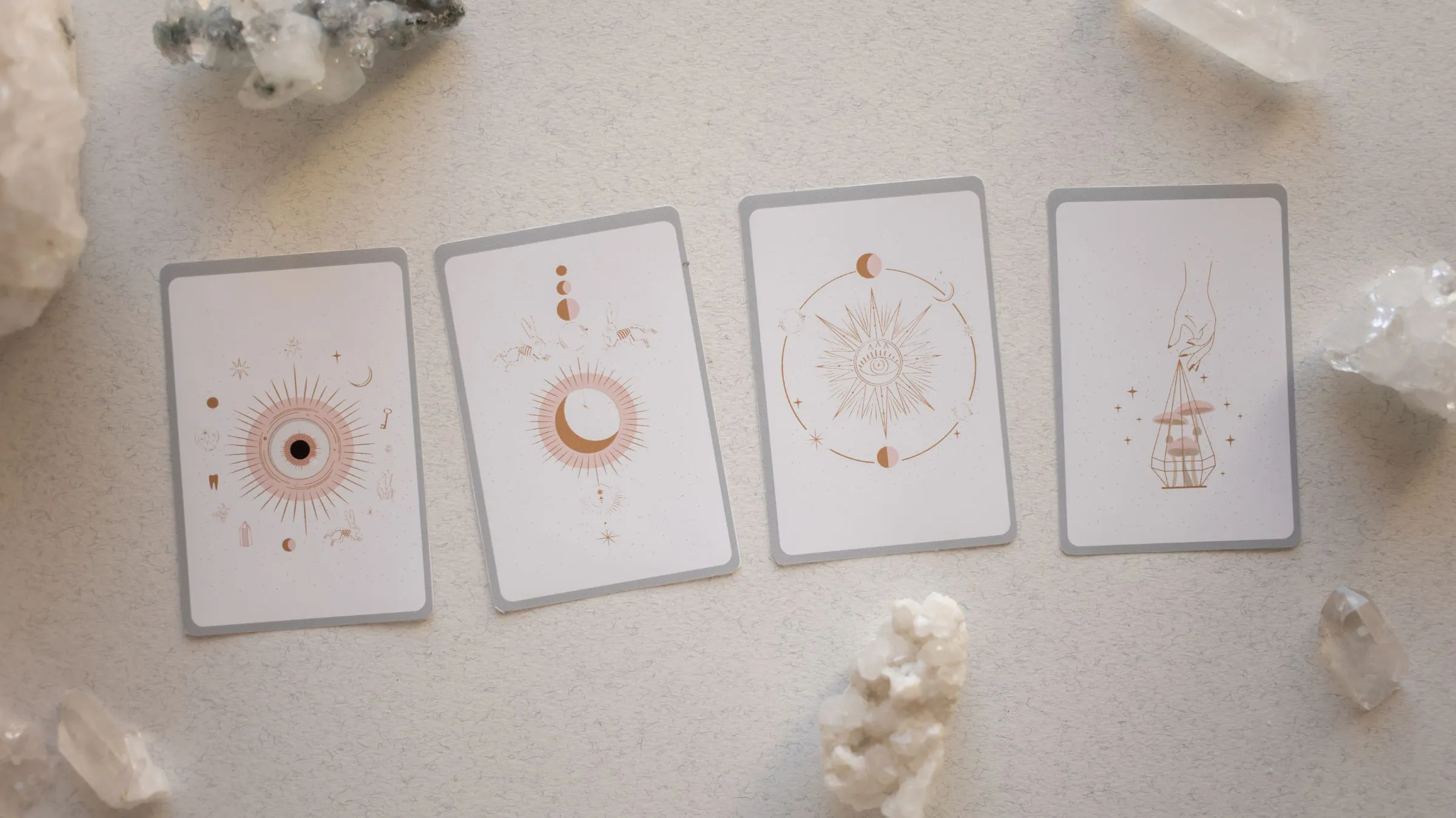 Four pale cards laid in a row among clear quartz crystals.